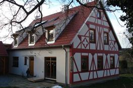 Das Haus ist fertig! Holzrahmenbauweise mit sichtbarem Dachstuhl, Außenwände z. T. verputzt, z. T. vorgeblendetes Fachwerk